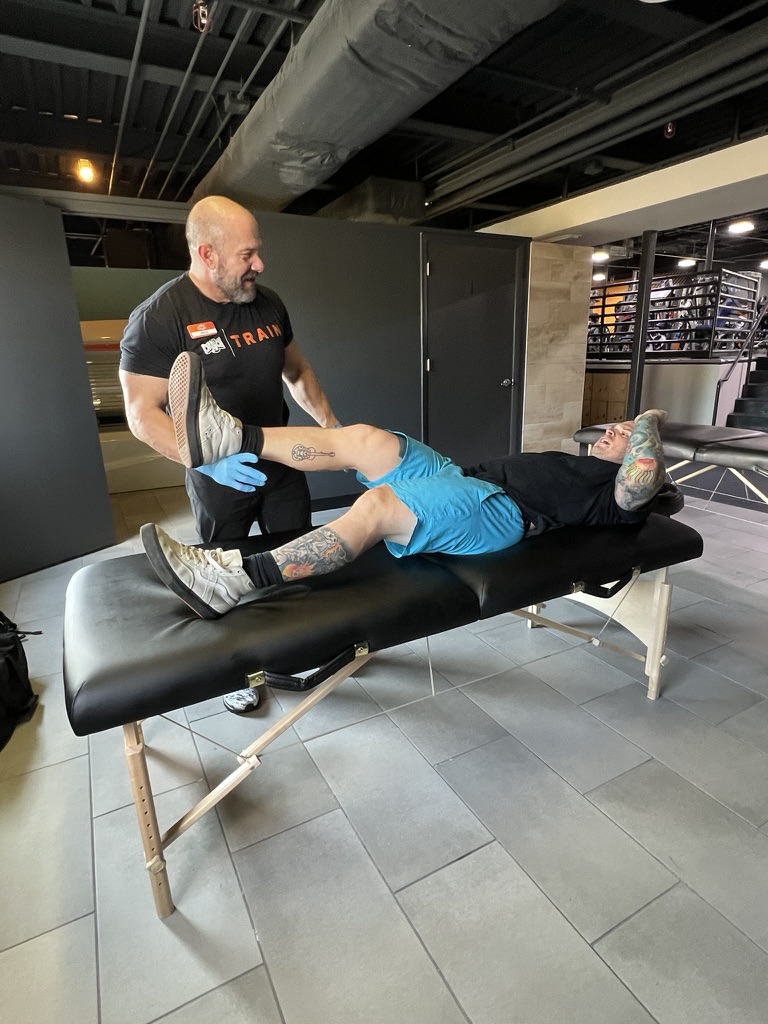 Pete Belcastro providing assisted stretching as part of post-workout recovery at a Tampa Bay gym – sports massage therapy to improve mobility and prevent injury for active individuals.